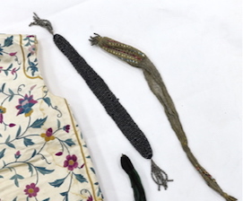 A collection of eight late 18th / early 19th century cut steel and other misers purses, a pair of yellow Regency ladies long shami leather gloves, an exotic feather hat ornament and a Chinese embroidered young boys waist